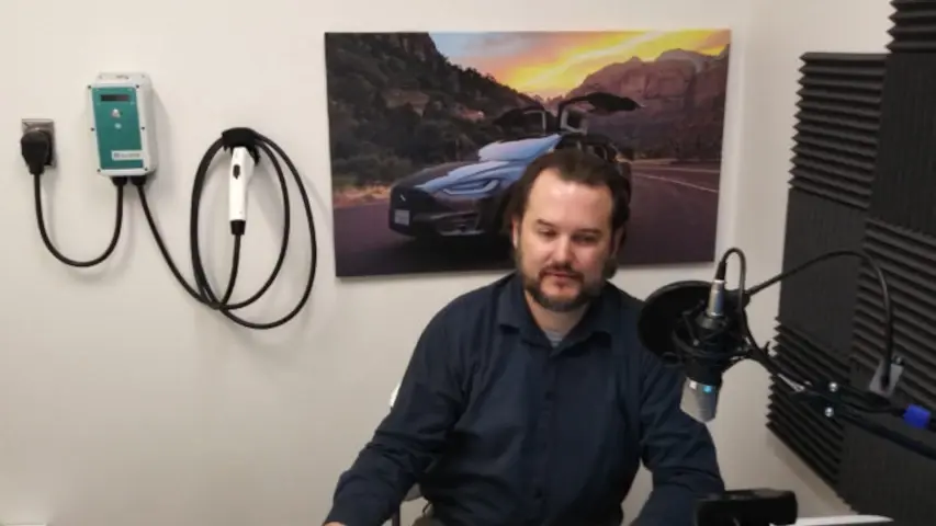 Christopher Howell of OpenEVSE recording the podcast! An OpenEVSE charger is on the wall behind him.